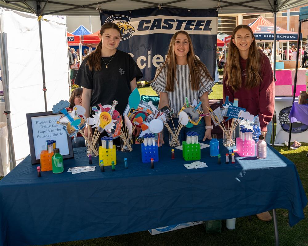 Students from Casteel High School stand and smile by their booth.